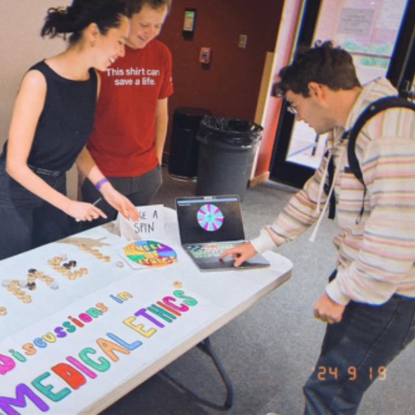 Three people at an info table on the Health Campus involvement Fair